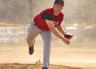 Tristan Rudenick fires a pitch to the plate against Melrose while a dust storm swirls behind him.